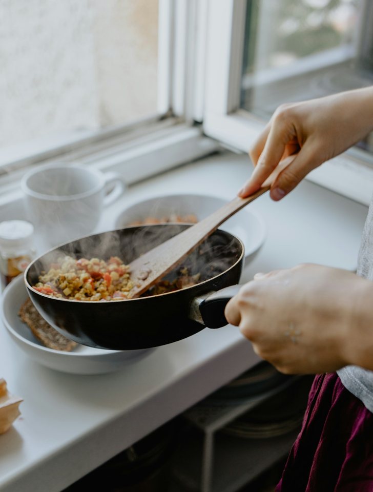 Préparation d’un repas dans une poêle, près d’une fenêtre