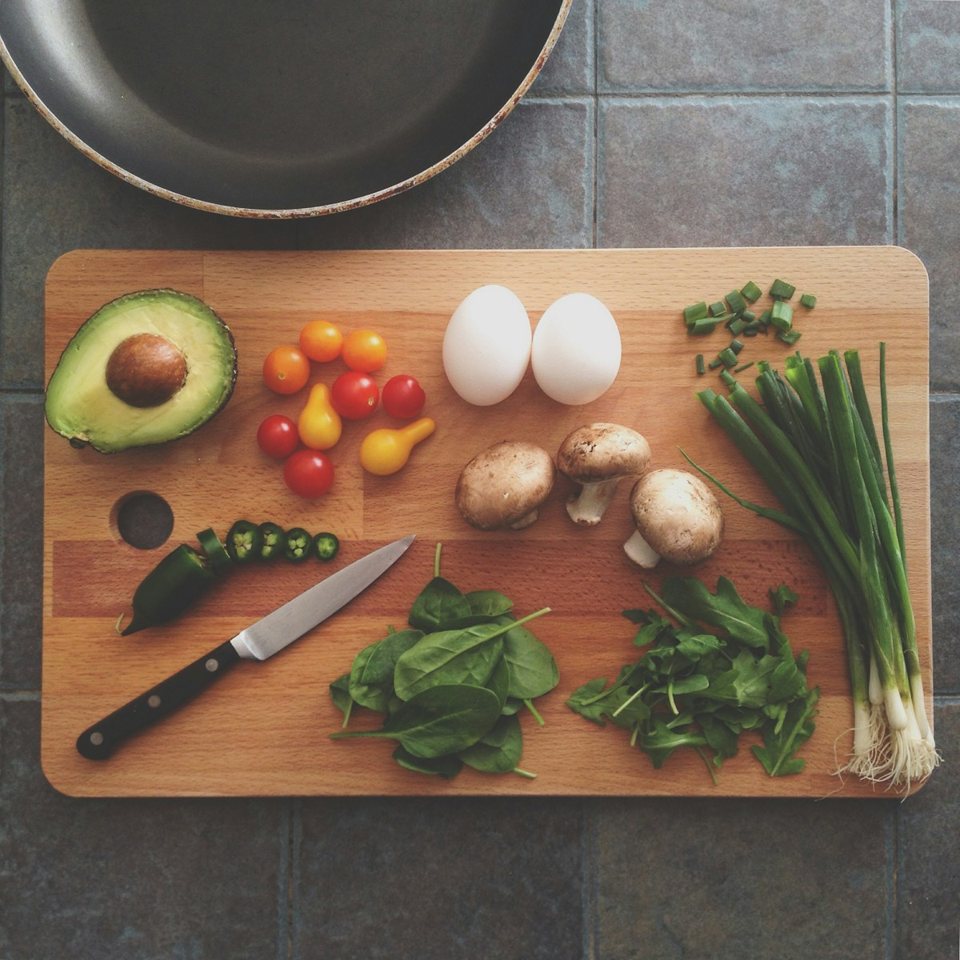 Ingrédients du quotidien sur une planche : œufs, avocat, tomates et champignons