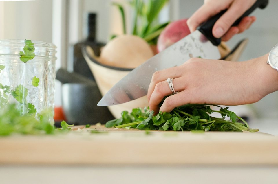 Mains découpant des herbes fraîches dans une cuisine